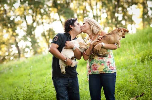 couple kissing with two dogs